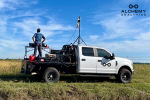 Man standing on bed of a truck with equipment for remote sensing.